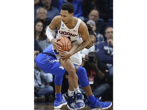 Connecticut's Jalen Adams, front tangles with Memphis' Kyvon Davenport during the first half an NCAA college basketball game, Sunday, Feb. 25, 2018, in Storrs, Conn.