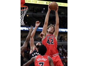 Chicago Bulls center Robin Lopez, right, rebounds a ball against Toronto Raptors center Jonas Valanciunas during the first half of an NBA basketball game Wednesday, Feb. 14, 2018, in Chicago.