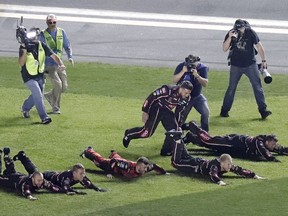 Austin Dillon, center, celebrates with his crew as they dive on the grass in the infield after winning the NASCAR Daytona 500 auto race at Daytona International Speedway, Sunday, Feb. 18, 2018, in Daytona Beach, Fla.