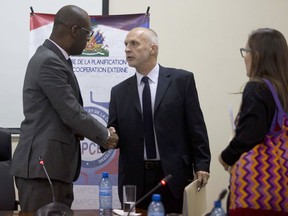 Oxfam International Regional Director for Latin America, Simon Ticehurst, center, shakes hands with Haiti's Minister of Planning and External Cooperation Aviol Fleurant after a meeting in Port-au-Prince, Haiti, Thursday Feb. 22, 2018. Fleurant says Oxfam will be suspended in the country for two months pending an investigation into sexual misconduct by employees of the aid group.