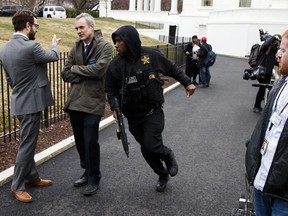 A Secret Service officer rushes past reporters after a vehicle rammed into a security barrier near the White House, Friday, Feb. 23, 2018, in Washington.