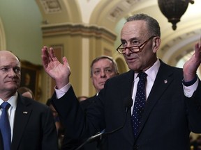 Senate Minority Leader Sen. Chuck Schumer of N.Y., right, responds to a reporter's question on Capitol Hill in Washington, Tuesday, Feb. 13, 2018, following the weekly Democratic policy luncheon. Schumer is joined by, Sen. Chris Coons, D-Del., left, and Sen. Dick Durbin, D-Ill., center.