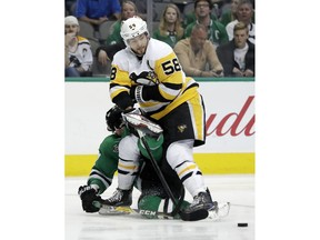 Pittsburgh Penguins defenseman Kris Letang (58) passes the puck as he fights off pressure from Dallas Stars right wing Alexander Radulov, of Russia, during the first period of an NHL hockey game Friday, Feb. 9, 2018, in Dallas.