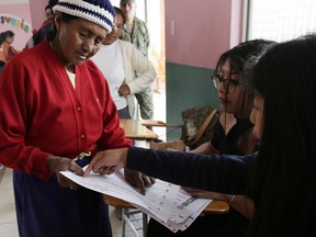 A woman gets her question answered by voting officials during a constitutional referendum called by President Lenin Moreno in Quito, Ecuador, Sunday, Feb. 4, 2018. Moreno called for the nationwide referendum that will include a question asking voters whether they want to revoke a law pushed forward by his predecessor allowing presidents to be indefinitely re-elected.