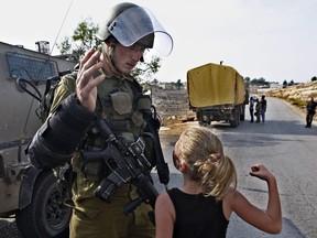 FILE - In this Nov. 2, 2012 file photo, then 12-year-old Ahed Tamimi tries to punch an Israeli soldier during a protest in the West Bank village of Nabi Saleh. Tamimi is to go on trial Tuesday, Feb. 13, 2018, before an Israeli military court, for slapping and punching two Israeli soldiers in December. Palestinians say her actions embody their David vs. Goliath struggle against a brutal military occupation, while Israel portrays them as a staged provocation meant to embarrass its military. Tamimi is one of an estimated 350 Palestinian minors in Israeli jails.