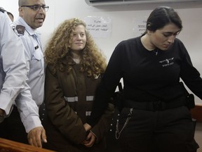FILE - In this Jan. 15, 2018 file photo, Ahed Tamimi is brought to a courtroom inside the Ofer military prison near Jerusalem. Tamimi is to go on trial Tuesday, Feb. 13, 2018, before an Israeli military court, for slapping and punching two Israeli soldiers in December. Palestinians say her actions embody their David vs. Goliath struggle against a brutal military occupation, while Israel portrays them as a staged provocation meant to embarrass its military. Tamimi is one of an estimated 350 Palestinian minors in Israeli jails.