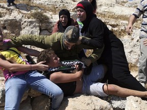 FILE - In this Aug, 28, 2015 file photo, Nariman Tamimi and her daughter Ahed try to free her son Mohammed from an Israeli soldier during a protest near the West Bank village of Nebi Saleh. Ahed is to go on trial Tuesday, Feb. 13, 2018, before an Israeli military court, for slapping and punching two Israeli soldiers in December. Palestinians say her actions embody their David vs. Goliath struggle against a brutal military occupation, while Israel portrays them as a staged provocation meant to embarrass its military. Tamimi is one of an estimated 350 Palestinian minors in Israeli jails.