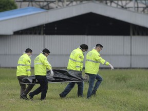 Police carry away the body of one of two people who fell from a departing airplane on the runway of the Jose Joaquin de Olmedo airport in Guayaquil, Ecuador.