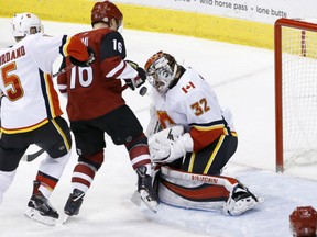 Calgary Flames' goaltender Jon Gillies goes low to block a shot despite the presence of Arizona Coyotes' Max Domi during NHL action Thursday in Glendale, Az. Gillies had 35 saves as the Flames posted a 5-2 victory.