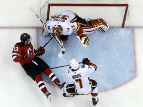 Calgary Flames goaltender David Rittich stops Nico Hischier of the New Jersey Devils from close in during NHL action Thursday night in Newark, N.J. Defenceman TJ Brodie lends assistance to Rittich, who made 29 saves in a 3-2 Calgary victory.