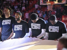 Miami Heat's Udonis Haslem and Dwyane Wade, right, bow their heads in a moment of silence as a large banner in memory of the victims of the Marjory Stoneman Douglas High School shooting is unfurled before an NBA basketball game in Miami on Saturday, Feb. 24, 2018 between the Heat and the Memphis Grizzlies.