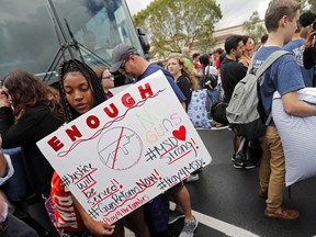 Tyra Hemans, 19, left, and Logan Locke, 17, right, students who survived the shooting at Stoneman Douglas High School, wait to board buses in Parkland, Fla., Tuesday, Feb. 20, 2018.   The students plan to hold a rally Wednesday in hopes that it will put pressure on the state's Republican-controlled Legislature to consider a sweeping package of gun-control laws, something some GOP lawmakers said Monday they would consider.