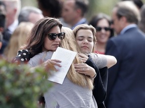 Mourners hug as they leave the funeral of Alaina Petty, in Coral Springs, Fla., Monday, Feb. 19, 2018.  Petty was a victim of Wednesday's mass shooting at Marjory Stoneman Douglas High School. Nikolas Cruz, a former student, was charged with 17 counts of premeditated murder on Thursday.