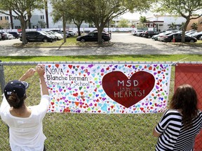 Volunteers hang banners around the perimeter of Marjory Stoneman High School in Parkland, Fla., to welcome back students who will be returning to school Wednesday two weeks after the mass shooting that killed 17 students and staff.