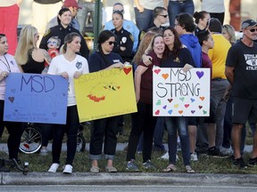 Supporters hold signs as students head back to classes at Marjory Stoneman Douglas High School in Parkland, Fla., Wednesday, Feb. 28, 2018. With a heavy police presence, classes resumed for the first time since several students and teachers were killed by a former student on Feb. 14.