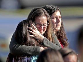 FILE - In this Wednesday, Feb. 14, 2018 file photo, students released from a lockdown embrace following a shooting at Marjory Stoneman Douglas High School that killed several students and three staff members, in Parkland, Fla. The latest mass shooting at the Florida high school has some pondering the improbable: Could this one actually bring some measure of change?