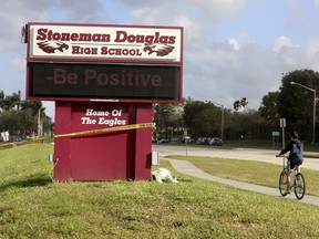 A bicyclist rides past a sign at  Marjory Stoneman Douglas High School on Friday, Feb. 23, 2018 in Parkland, Fla. Teachers and administrators returned for the first time  since the Valentine's Day shooting that killed several people.