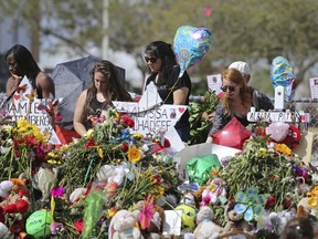 Mourners bring flowers as they pay tribute at a memorial for the victims of the shooting at Marjory Stoneman Douglas High School on Sunday, Feb. 25, 2018, in Parkland, Fla.