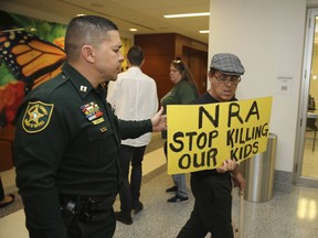 A Broward County sheriff's deputy escorts a protestor away from the door of the courtroom where a hearing was held for school shooting suspect Nikolas Cruz, Thursday, Feb. 15, 2018, at Broward County Court in Fort Lauderdale, Fla.  Cruz is accused of opening fire Wednesday at Marjory Stoneman Douglas High School in Parkland, Fla., killing more than a dozen people and injuring several.