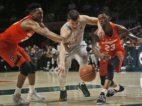 Syracuse guards Tyus Battle, left, and Frank Howard, right, battle for the ball with Miami guard Dejan Vasiljevic, center, during the first half of an NCAA college basketball game, Saturday, Feb. 17, 2018, in Coral Gables, Fla.