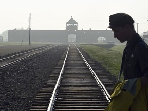 FILE - In this July 29, 2016 file photo a man crosses the iconic rails leading to the former Nazi death camp of Auschwitz-Birkenau prior to a visit by Pope Francis, in Poland. The office of Polish President Andrzej Duda said the leader will on Tuesday, Feb. 6, 2018 announce his decision on whether to sign legislation penalizing certain statements about the Holocaust.