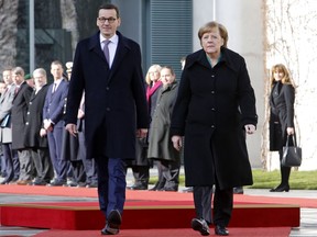 German Chancellor Angela Merkel, right, and Polish Prime Minister Mateusz Morawiecki review the guard of honor during a welcoming ceremony prior to a meeting in the chancellery in Berlin, Germany, Friday, Feb. 16, 2018.