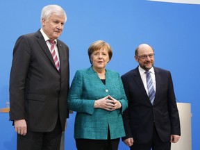 German Chancellor Angela Merkel, Chairwoman of the Christian Democratic Union, CDU, is flanked by Martin Schulz, chairman of the Social Democratic Party, SPD, and Bavarian Governor Horst Seehofer, chairman of the Christian Social Union, CSU, during a press statement after Merkel's conservatives and Germany's main center-left party reached a deal to form a new coalition government after a final session of talks that dragged on for 24 hours in the headquarters of the Christian Democratic Union in Berlin, Germany, Wednesday, Feb. 7, 2018.