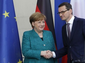 German Chancellor Angela Merkel, left, and Polish Prime Minister Mateusz Morawiecki shake hands as they pose for a photograph after a press conference after a meeting in the chancellery in Berlin, Germany, Friday, Feb. 16, 2018.