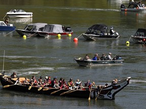 File - In this May 4, 2011 file photo, a group of people in a large canoe head upriver into scores of fishing boats during the Spring Chinook Salmon run on the Willamette River in Oregon City, Ore. Federal officials are considering putting a once-flourishing West Coast salmon on the list of threatened or endangered species. The National Marine Fisheries Services said Tuesday, Feb. 27, 2018, it will investigate whether to give protected status to spring-run Chinook salmon in and around the Klamath River.