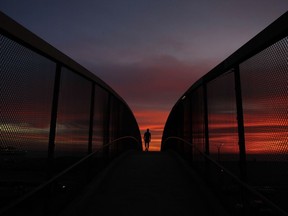 FILE - In this Jan. 16, 2018 file photo, Mark Waissar, 49, is silhouetted against sunset as he walks on an overpass above the Pacific Coast Highway in Santa Monica, Calif. California's water managers are carrying out their mid-winter snowpack survey Thursday, Feb. 1, 2018, as the winter's dry spell persists. Some Southern California areas including Los Angeles have received only one significant rain in months, and that rain, in January, caused deadly mudslides.