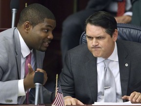 In this March 9, 2017, file photo, Rep. Byron Donalds, R-Naples, left, confers with Rep. Cord Byrd, R-Neptune Beach, in Tallahassee, Fla. Donalds is the lead sponsor of a proposal that would allow parents whose children have been bullied at public schools to obtain state vouchers to help pay tuition at a private school.