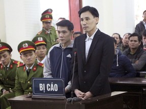 Hoang Duc Binh, center right, and Nguyen Nam Phong, center left, appear in court in the central province of Nghe An, Vietnam, Tuesday, Feb. 6, 2018. Binh was convicted of abusing democratic freedoms to infringe on the interest of the state and opposing officers on duty and given 14 years in prison while Phong received two years in jail for opposing officers on duty at the trial that lasted half a day.