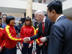 FIFA President Gianni Infantino, center, shakes hands with a Vietnamese female football player in Hanoi, Vietnam, Thursday, Feb. 8, 2018. Infantino is on one-day visit to the Southeast Asian country to boost cooperation between the world football body and Vietnam.