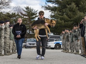 Rico the dog, carried by his former handler, Jason Spangenberg, is saluted by members of the 436th Security Forces Squadron as he is taken to the vet to be euthanized for a terminal spinal cord disease.