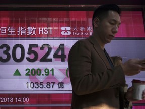 A man walks past a bank electronic board showing the Hong Kong share index at Hong Kong Stock Exchange Thursday, Feb. 8, 2018. Asian stock markets were mixed Thursday with some benchmarks erasing early morning gains. Investors remained skittish after this week's financial turmoil and overnight losses on Wall Street.
