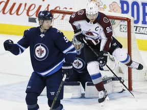 Colorado Avalanche's Gabriel Landeskog attempts to deflect the shot from the point past Jets goaltender Connor Hellebuyck as Tyler Myers defends during third period NHL action in Winnipeg on Saturday night.