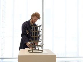 In this Monday, Feb. 12, 2018 photo, Thomas Huston, departmental technician, modern and contemporary department, tweaks "Bottle Rack", by conceptual artist Marcel Duchamp, at the Art Institute of Chicago in Chicago. Art Institute President and Eloise W. Martin Director James Rondeau says the piece "is among the most pivotal, landmark works in Marcel Duchamp's profoundly influential body of work."
