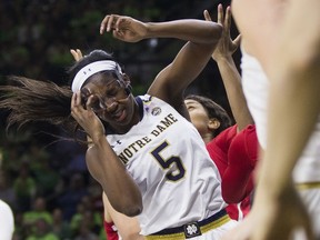 Notre Dame's Jackie Young (5) grabs for her facemask  after being hit in the face during the first half of an NCAA college basketball game against NC State Sunday, Feb. 25, 2018, in South Bend, Ind.