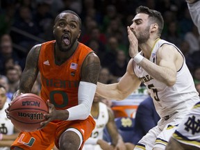 Miami's Ja'Quan Newton (0) looks for a shot under the basket as Notre Dame's Matt Farrell (5) defends during the first half of an NCAA college basketball game Monday, Feb. 19, 2018, in South Bend, Ind.