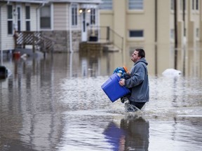 Roget Willemin carries his belongings out of his flooded home on Emerson Avenue Wednesday, Feb. 21, 2018, in South Bend, Ind.