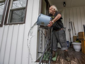 Robert Forler tosses a bucket out water off his front porch as he tries to clear standing water from his home on Emerson Avenue Wednesday, Feb. 21, 2018, in South Bend, Ind.