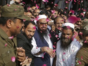 FILE - In this Thursday, Oct. 19, 2017 file photo, supporters of Hafiz Saeed, center, head of the Pakistani religious party, Jamaat-ud-Dawa, is showered with rose petals by his supporters as he arrives to a court in Lahore, Pakistan. Pakistan has started seizing assets and funds belonging to Islamic charities linked to a radical cleric wanted by Washington who was released from detention late last year.