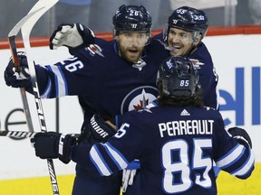 Blake Wheeler, left, is congratulated by teammates Mark Scheifele, right, and Mathieu Perreault after scoring one of his two goals in Winnipeg's 6-1 win over the Colorado Avalanche in NHL action Friday night in Winnipeg.