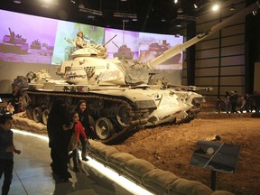 In this Thursday, Feb. 1, 2018 photo, a family walk past a tank at the Royal Tank Museum in Amman, Jordan. The museum displaying 110 battle-worn tanks from a century of wars in the Middle East and from more distant conflicts opened last week. Curators collected the armored vehicles over the past decade, including some that served in both sides of the Iran-Iraq war and in the conflicts between Israel and its Arab neighbors in the Golan Heights, Jordan and Jerusalem.