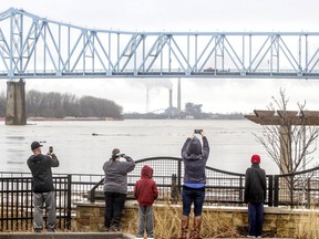 A crowd of onlookers take photographs of the rising level of the Ohio River as it encroaches the barrier wall at Smothers Park on Saturday, Feb. 24, 2018, in Owensboro, Ky.   Forecasters warned people living along rivers, streams and creeks in southern Ohio, southeastern Indiana and northern Kentucky to be especially cautious and prepared for rapid rises.