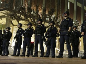 FILE - In this Feb. 1, 2017 file photo, University of California, Berkeley police officers guard the building where Breitbart News editor Milo Yiannopoulos was to speak in Berkeley, Calif. In a cost breakdown released Sunday, Feb. 4, 2018, the university said it spent almost $4 million on security during a one-month spate of free speech events last year, when the famously liberal campus became a flashpoint for country's political divisions.