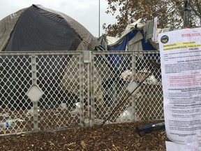 FILE - In this Jan. 8, 2018 file photo, signs warning homeless residents they'll need to move out of a two-mile long encampment are posted in Anaheim, Calif. A long-running dispute over a Southern California county's plans to shut down the massive homeless encampment faces a key day in court. Homeless residents and their advocates are expected to argue in U.S. court Tuesday, Feb. 13, that Orange County can't remove them from a riverbed bike trail without adequate housing options. Officials say they've offered shelter beds and housing. The lawsuit is being watched by homeless advocates nationwide amid a rise in encampments.