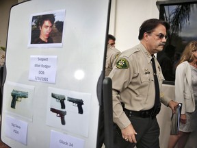 FILE - In this May 24, 2014 file photo, Santa Barbara County Sheriff Bill Brown, right, walks past a board displaying photos of gunman Elliot Rodger and the weapons he used in a mass shooting in Isla Vista, Calif., after a news conference in Santa Barbara, Calif. A growing number of states have passed laws or are considering bills allowing courts to temporarily remove guns from individuals deemed a danger to themselves or others, an intervention that advocates say stops shootings and suicides by disturbed individuals.