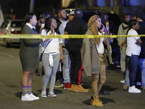 Onlookers watch as police investigate the scene of a Mardi Gras day shooting in the lower Ninth Ward in New Orleans, Tuesday, Feb. 13, 2018.