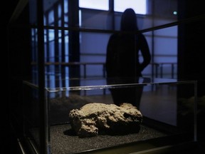 A staff member poses for photographs next to the only remaining piece of the 130 ton, 250 meter long fatberg, removed from the sewers in the Whitechapel area of east London in the latter months of 2017, displayed during a media preview at the Museum of London in London, Thursday, Feb. 8, 2018. The sample is being displayed as part of the 'Fatberg!' exhibition, which opens to the public from Feb. 9 to July 1 and details the work involved in clearing a fatberg from a sewer. The Whitechapel fatberg was formed from a mass of oil and grease congealed with wet wipes and other sanitary products.